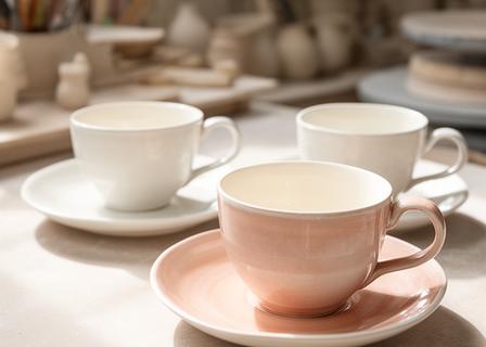Kaffeetassen und Teetassen in einer hellen Werkstatt mit fein strukturierter Glasur